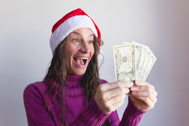 Gelukkige vrouw met rode kerstmuts met dollarbiljetten op witte achtergrond Lucky lady op winter