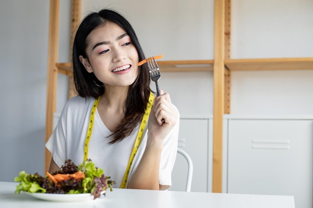 Gelukkige vrouw met schotel groente voor gezonde voeding met een glimlach in de gezondheidszorg. Verse biologische vegetarische salade eten.