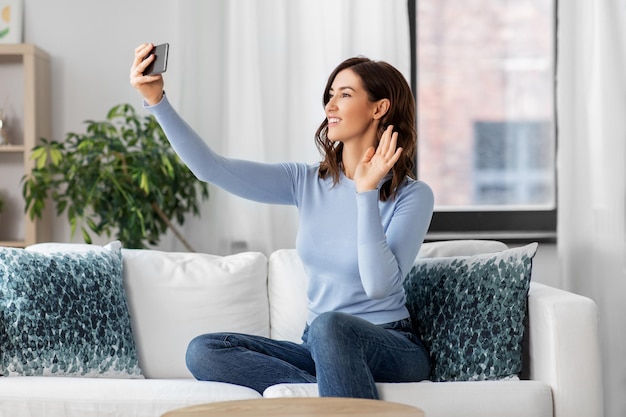 Gelukkige vrouw met smartphone die thuis een selfie maakt