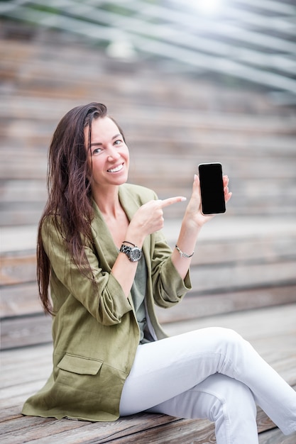 Gelukkige vrouw met smartphone in openlucht in de stad