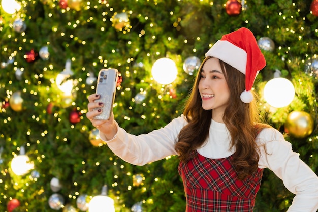 Gelukkige vrouw met smartphone met kerstboom, kerst vieren