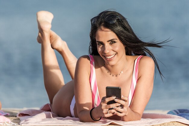 Gelukkige vrouw met smartphone ontspannen op het strand