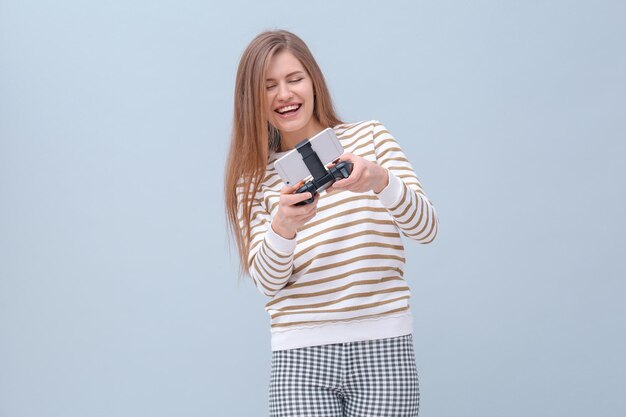 Gelukkige vrouw met videogamecontroller voor smartphone op gekleurde achtergrond