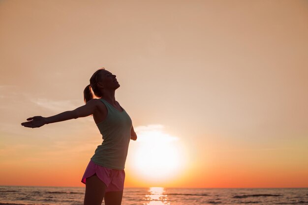 Gelukkige vrouw na training staan in de zonsondergang