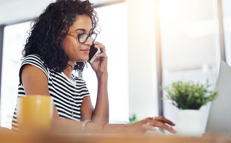 Foto gelukkige vrouw of student met een telefoongesprek en laptop voor e-learning feedback en afstandswerk aan een essay glimlach vrouwelijke persoon en online cursus met mobiel voor advies en hulp van de universitaire hotline