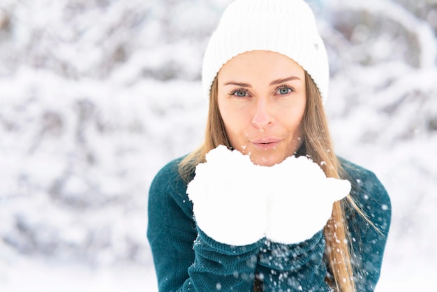 Gelukkige vrouw op de achtergrond van het bos, sneeuw valt op het meisje, het vrouwtje glimlacht in de winter.