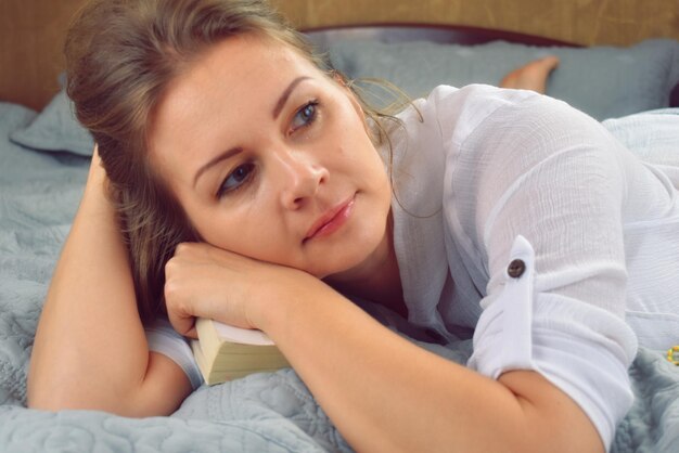 Gelukkige vrouw op het bed Het meisje en het boek Liever thuis ontspannen