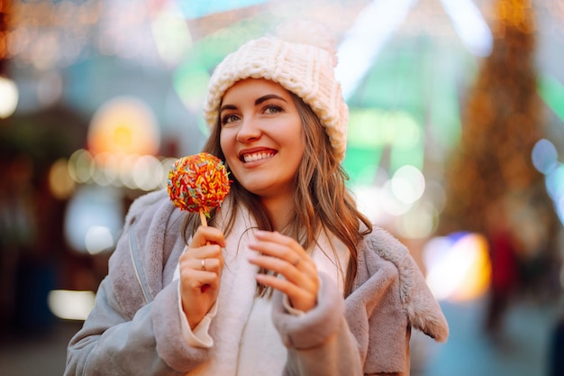 Gelukkige vrouw op kerstmarkt met gekarameliseerde appel. Buitenactiviteiten op Kerstmis.