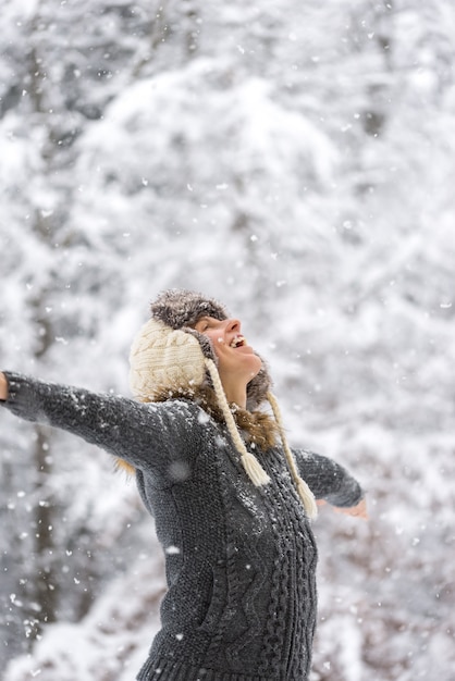 Gelukkige vrouw op vallende sneeuw met open armen