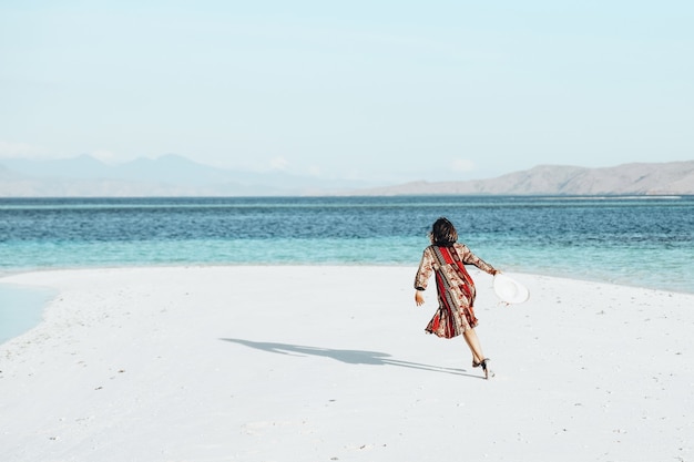 Gelukkige vrouw rennen en dansen op wit zandstrand