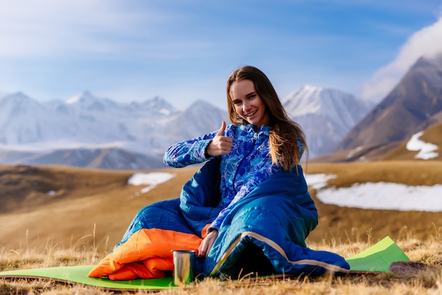 Gelukkige vrouw toerist zit op de achtergrond van bergen