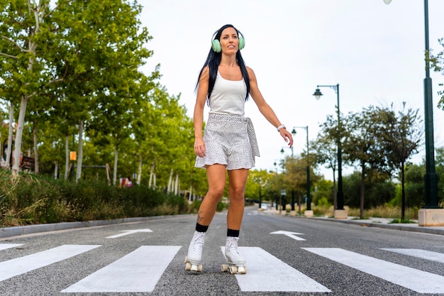 Gelukkige vrouw van middelbare leeftijd die jurk draagt en glimlacht terwijl ze op de asfaltweg skate op zonnige dag