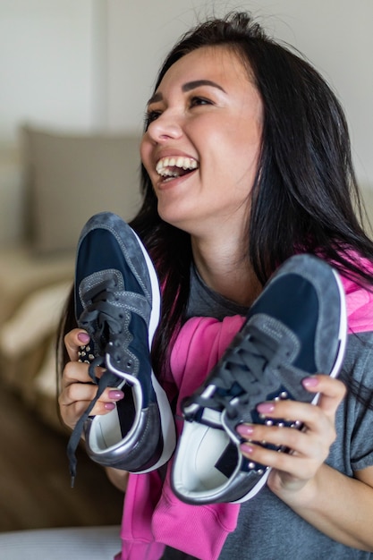 Gelukkige vrouw verheugt zich met nieuwe sneakers met plezier en positieve emotie verkoop korting kopen sale