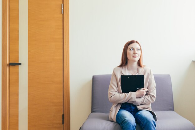 Gelukkige vrouw verwacht positieve nieuwe en goede interviewresultaten in de wachtkamer