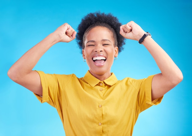 Gelukkige vrouw vuist pomp en viering voor het winnen van promotie of bonus tegen een blauwe studio achtergrond Afrikaanse vrouwelijke persoon genieten van overwinning verkoop of korting in geluk voor prestaties of doelen