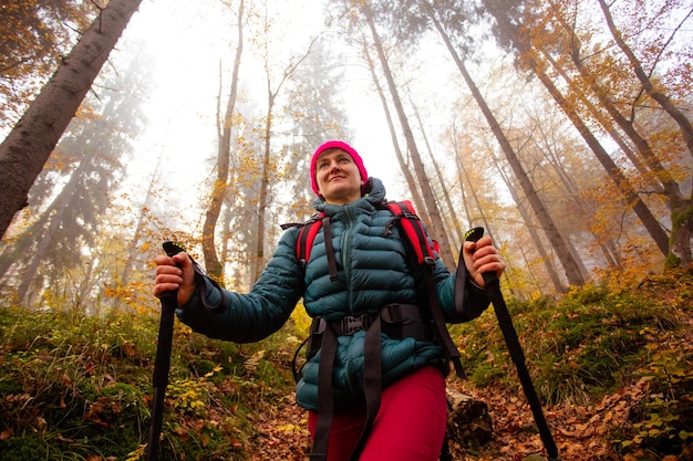 Gelukkige vrouw wandelaar loopt in het prachtige herfstbos