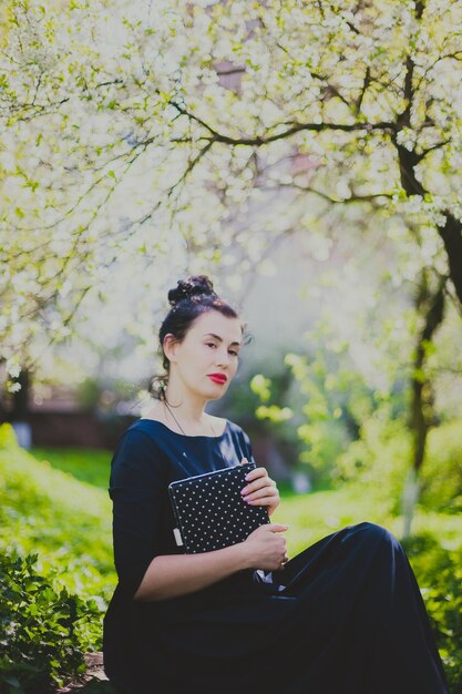 Gelukkige vrouw zitten in de lente kersentuin