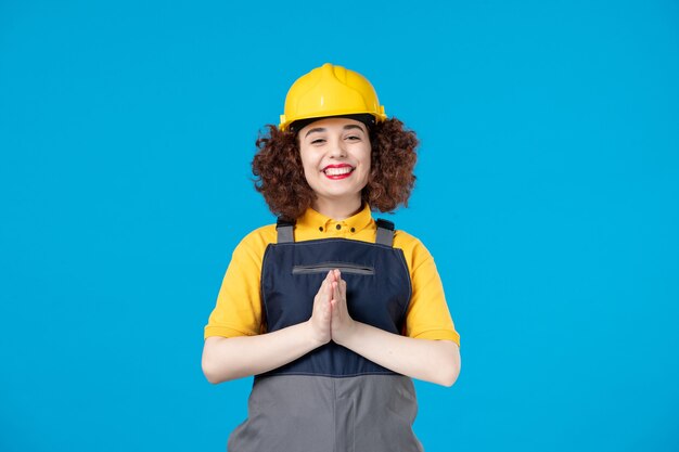 Gelukkige vrouwelijke bouwer in uniform op blauw