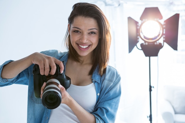 Gelukkige vrouwelijke fotograaf die zich in studio bevindt