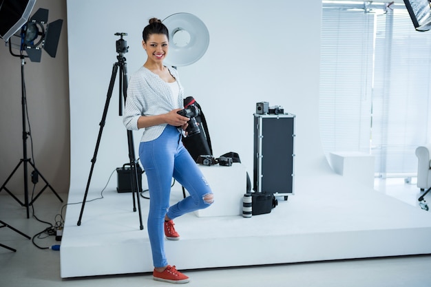 Gelukkige vrouwelijke fotograaf die zich in studio bevindt