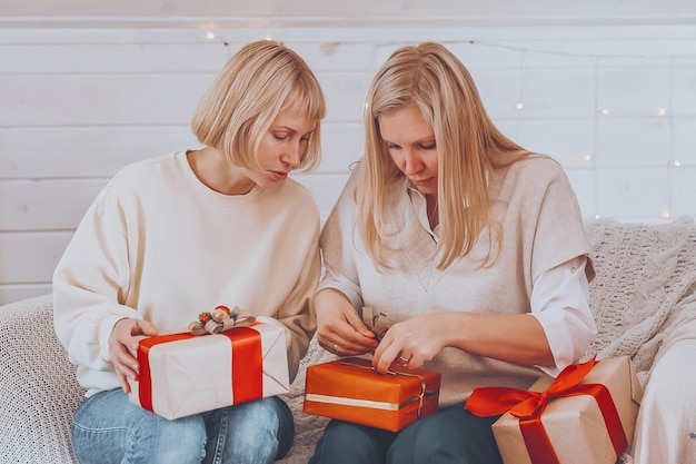 Gelukkige vrouwelijke moeders bereiden zich voor op Kerstmis Nieuwjaar pack geschenken thuis terwijl ze in de buurt van de kerstboom zitten Wintervakantie huisdecoratie concept