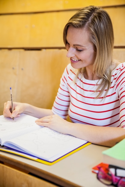 gelukkige vrouwelijke student het schrijven van notities op de universiteit