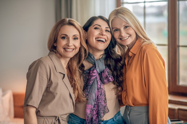 Gelukkige vrouwen. Drie vrouwen in elegante outfits die glimlachen en er gelukkig uitzien