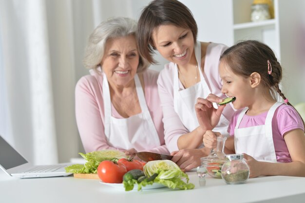 Gelukkige vrouwen met een klein meisje dat in de keuken kookt