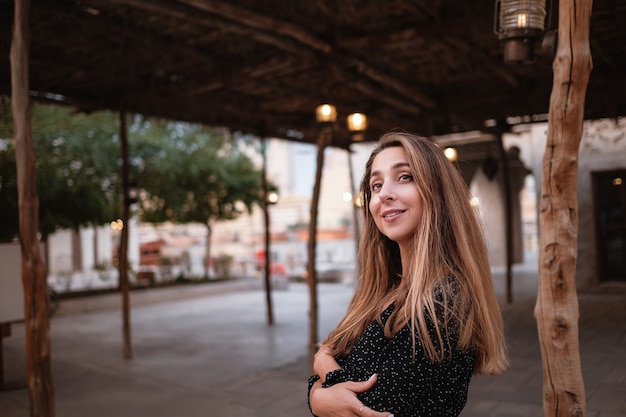 Gelukkige vrouwenreiziger die zwarte kleding draagt die door de straten van een oude Arabische stad of een dorp in het midden van de woestijn loopt. Traditionele Arabische olielampen in de straat Al Seef Dubai