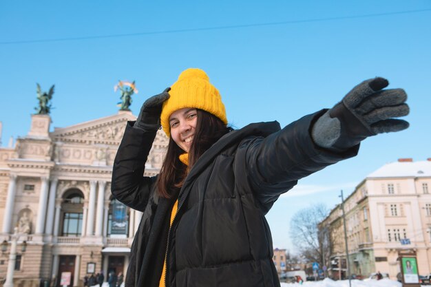 Gelukkige vrouwenreiziger voor operagebouw in het winterseizoen van lviv, besneeuwde stad