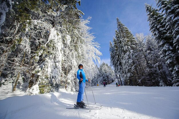 Gelukkige vrouwenskiër op een skihelling in het bos