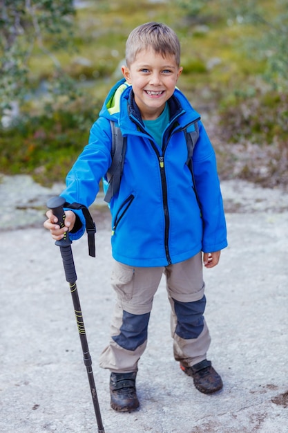 Gelukkige wandeljongen met trekkingstokken in de bergen. Noorwegen