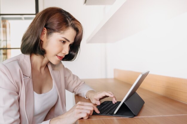 Gelukkige werkende vrouw gebruikt een tablet op kantoor