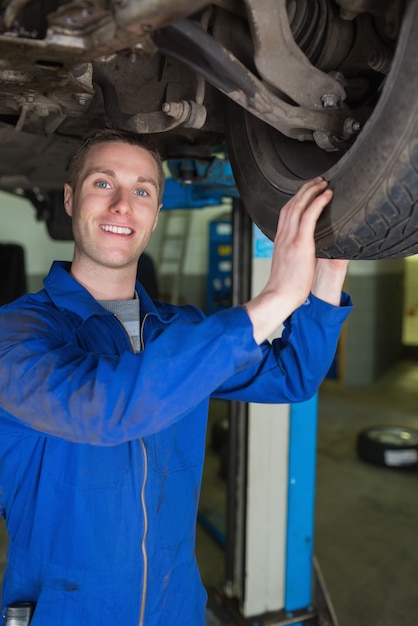 Gelukkige werktuigkundige die autoband onderzoekt