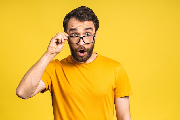 Gelukkige winnaar! Portret van een geschokte, verbaasde jonge mannelijke man houdt de mond wijd open, verrast, drukt grote verbazing uit. Geïsoleerd over roze gele achtergrond.