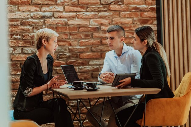 Gelukkige zakenlieden die vrolijk glimlachen tijdens een vergadering in een koffieshop Groep succesvolle zakenprofessionals die als team werken op een multiculturele werkplek