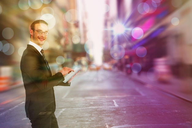 Gelukkige zakenman die zijn tabletpc gebruikt tegen de onscherpe straat van New York