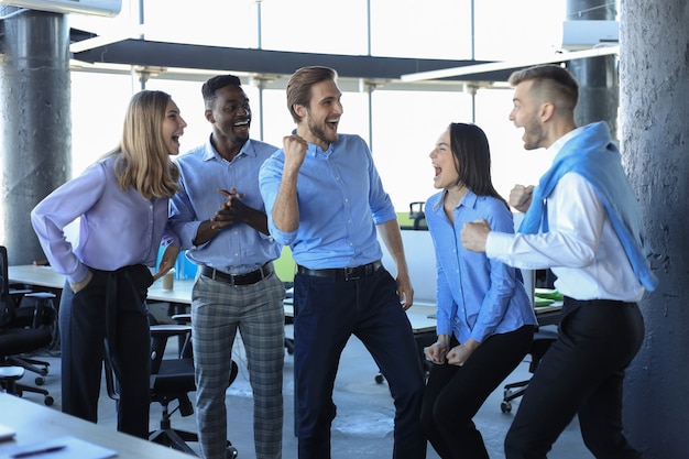 Gelukkige zakenmensen lachen op kantoor. Succesvolle teamgenoten maken grapjes en hebben samen plezier op het werk.