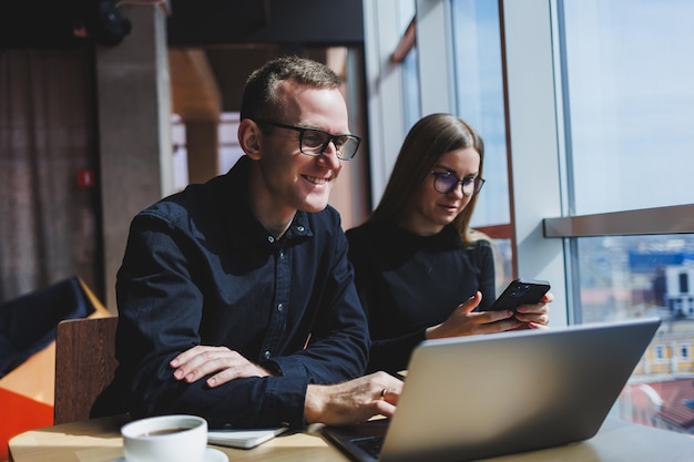 Gelukkige zakenmensen zitten aan tafel praten lachend bespreken zakelijke documenten lachende collega's werken samen op kantoor tijdens een briefing brainstormen op een vergadering