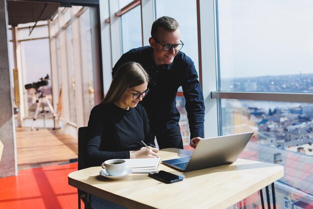 Gelukkige zakenmensen zitten aan tafel praten lachend bespreken zakelijke documenten lachende collega's werken samen op kantoor tijdens een briefing brainstormen op een vergadering