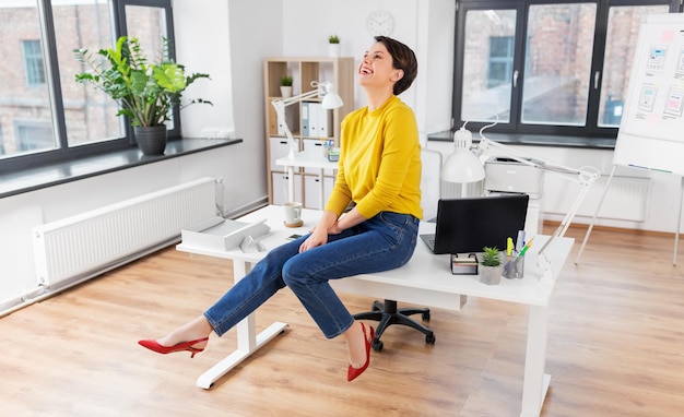 Gelukkige zakenvrouw zit op het bureau.