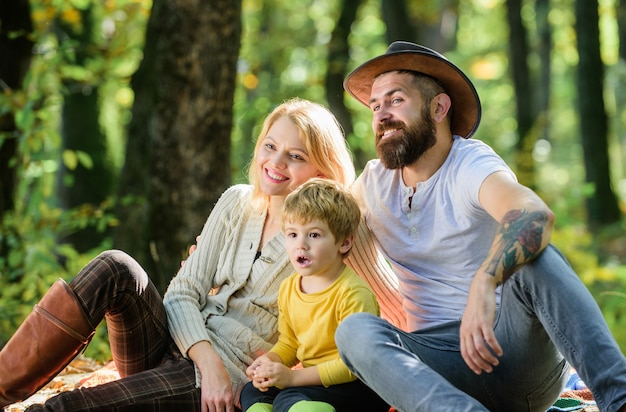 Gelukkige zoon met ouders ontspannen in herfstbos. Zonnig weer. Gezond eten. Moeder, cowboyvader houden van hun kleine jongenskind. Lente gevoel. Fijne familiedag. Familie picknick. Spreek positiviteit uit.