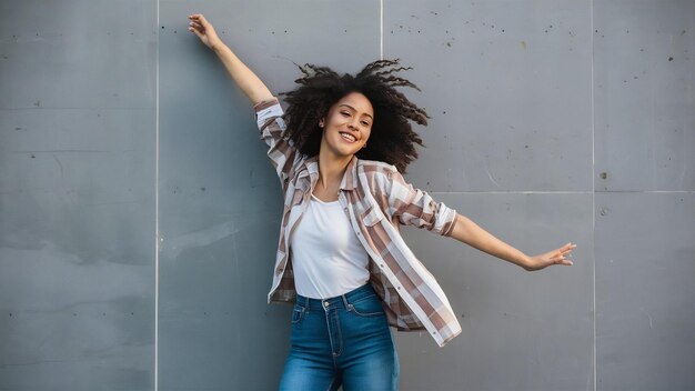 Foto gelukkige zorgeloze jonge vrouw die over de grijze muur danst