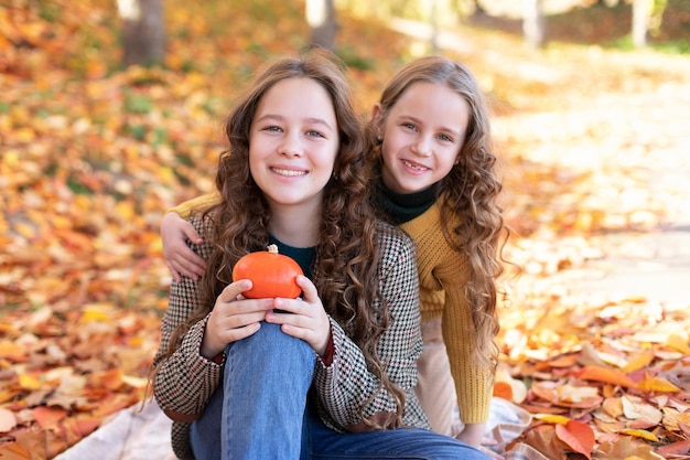 Gelukkige zusjes knuffelen op een herfstachtergrond voor halloween