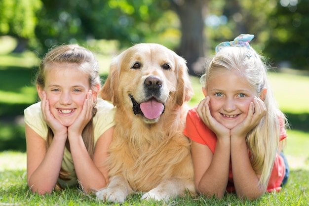 Gelukkige zusters die bij camera met hun hond glimlachen