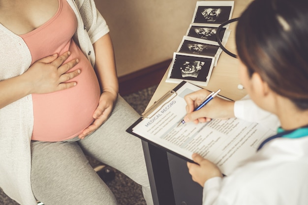 Gelukkige zwangere vrouw bezoekt gynaecoloog arts in ziekenhuis of kliniek voor zwangerschapsconsulent.