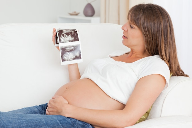 Gelukkige zwangere vrouw die de echoscopie van haar baby bekijkt