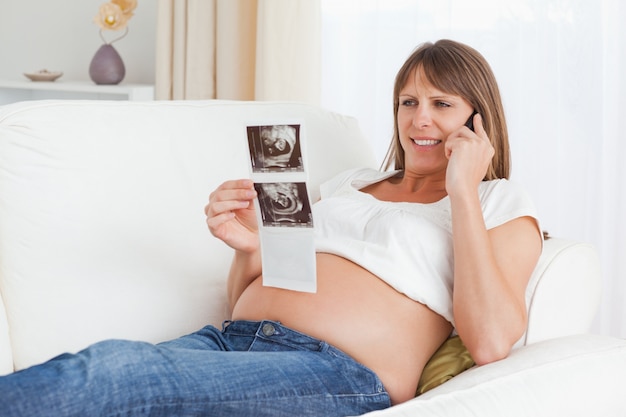 Gelukkige zwangere vrouw die over de echoscopie van haar baby spreekt