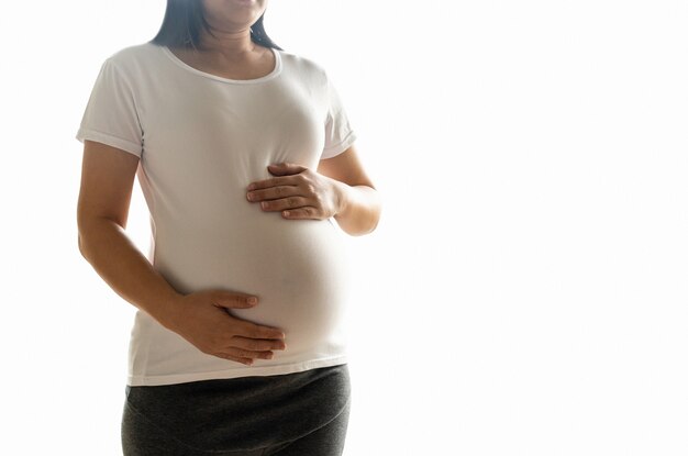 Gelukkige zwangere vrouw met baby in zwangere buik die op witte achtergrond wordt geïsoleerd.