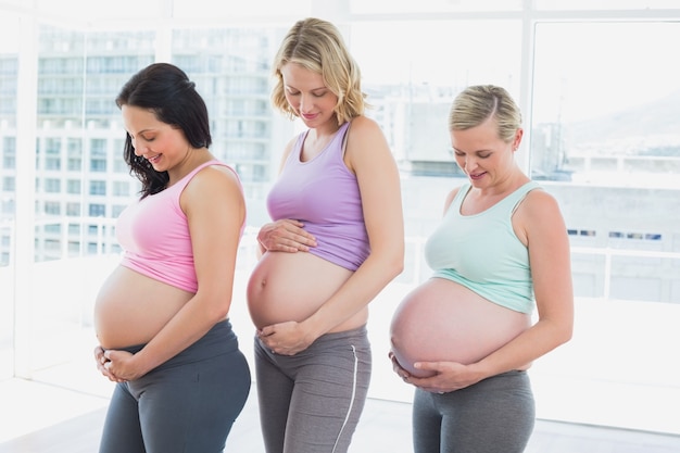 Gelukkige zwangere vrouwen die zich op een rij bevinden die builen bekijken